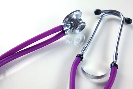 Medical violet  stethoscope lying in white backgroundの写真素材