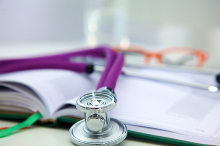 Stethoscope lying on a notebook computer in the background and books.の写真素材