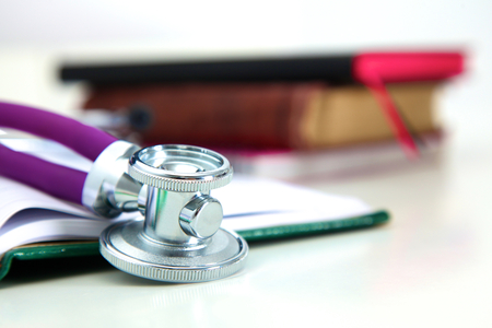 Stethoscope lying on a notebook computer in the background and books.の写真素材