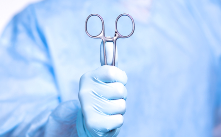 Detail shot of steralized surgery instruments with a hand grabbing a tool.の写真素材