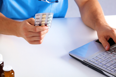 the doctor writes a prescription pill on the computer.の写真素材