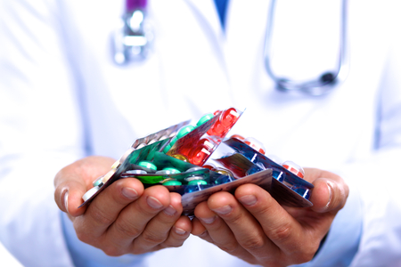 A young doctor holds the patient's hand with pills.の写真素材