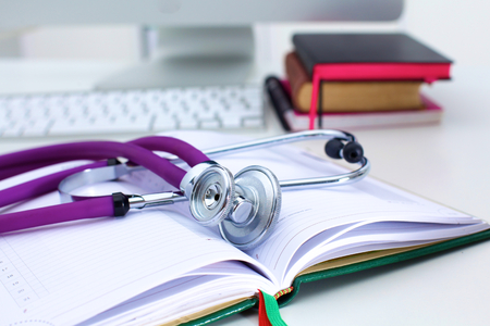 Stethoscope lying on a table on an open book.の写真素材