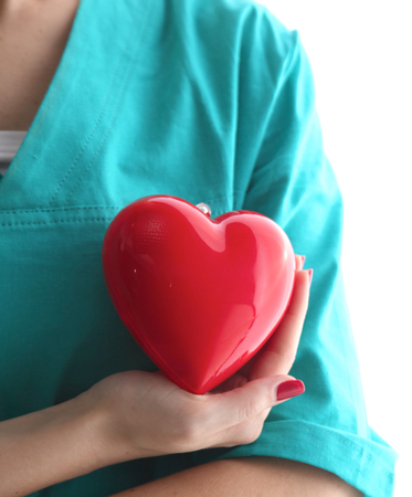 Young woman doctor holding a red heart, in office.の写真素材