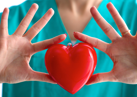 Young woman doctor holding a red heart, in office.の写真素材