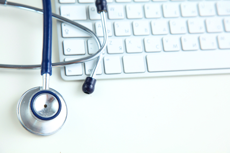 A medical stethoscope near a laptop on table, on whiteの写真素材