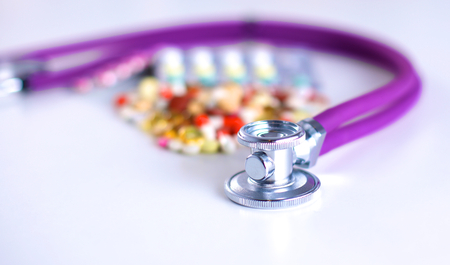 Close up of pills spread over the table with stethoscope and heart lying besideの写真素材