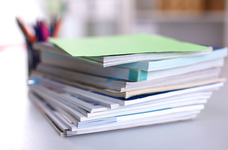 A stack of documentation is on the desktop in the officeの写真素材