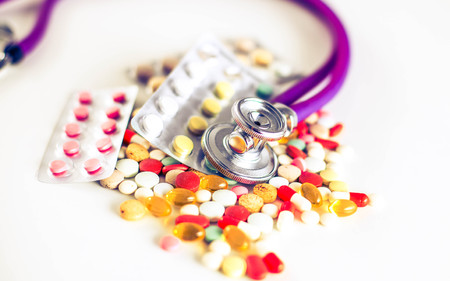 Close up of pills spread over the table with stethoscope and heart lying besideの写真素材