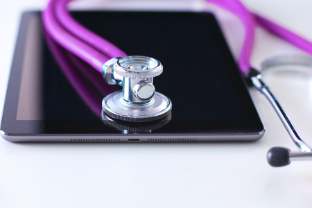 Tablet computer with a stethoscope lie on a table.の写真素材