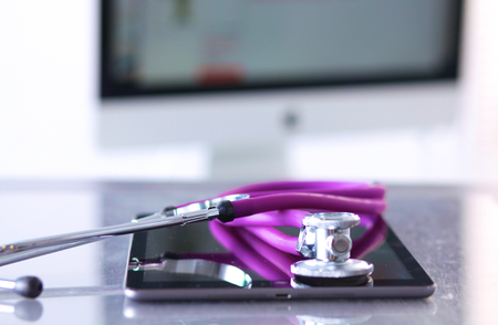 Tablet computer with a stethoscope lie on a table.の写真素材