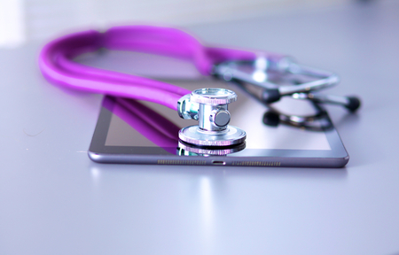 Tablet computer with a stethoscope lie on a tableの写真素材