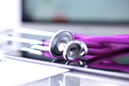 Tablet computer with a stethoscope lie on a table.の写真素材