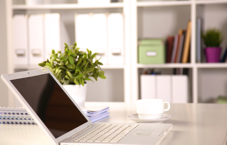 Close up view of a work desk interior with a laptop computer, a cup of coffee and white curtains on a sunny dayの写真素材