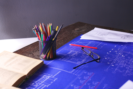 Architectural blueprints and blueprint rolls and a drawing instruments on the worktableの写真素材