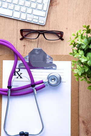 A medical stethoscope near a laptop on a wooden table, on whiteの写真素材