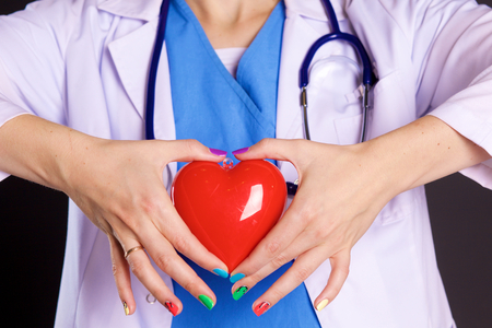 Female doctor with the stethoscope holding heartの写真素材