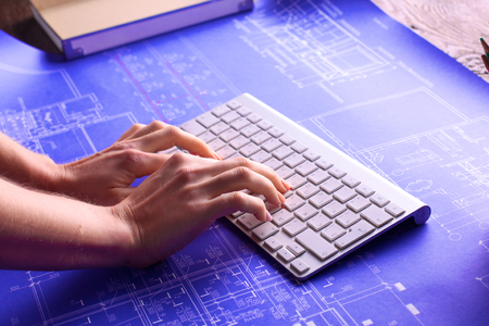 Architectural blueprints and blueprint rolls and a drawing instruments on the worktableの写真素材