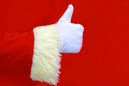 Santa Claus hand presenting your christmas text or product over red background with copy spaceの写真素材