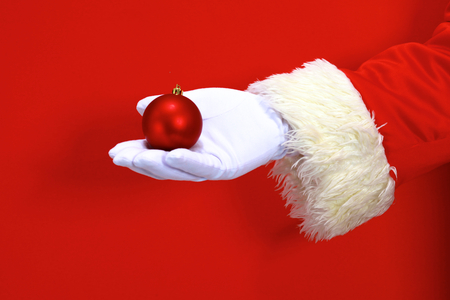 Santa Claus hand presenting your christmas text or product over red background with copy spaceの写真素材