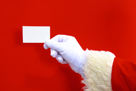 Santa Claus hand presenting your christmas text or product over red background with copy spaceの写真素材