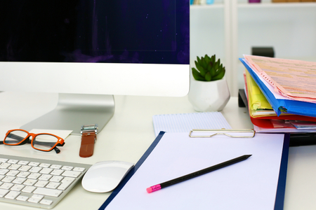 Office table with blank notepad and laptopの写真素材