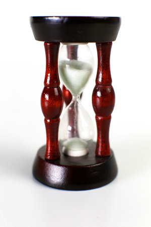 Vintage hourglass on dark background with long shadow