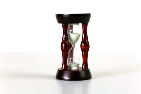Vintage hourglass on dark background with long shadow