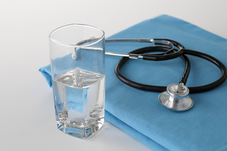 stethoscope a glass of water and pills on a uniformの写真素材