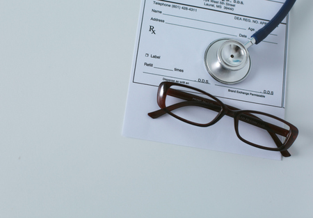 medical stethoscope and glasses lie on the tableの写真素材