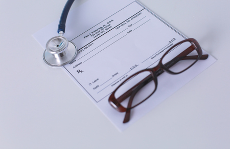 medical stethoscope and glasses lie on the tableの写真素材