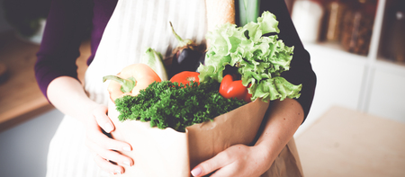 Healthy positive happy woman holding a paper shopping bag full of fruit and vegetablesの写真素材