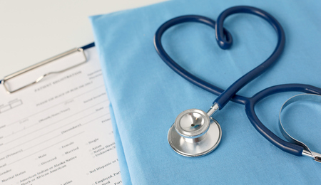 A stethoscope shaping a heart and a clipboard on a medical uniform, closeupの写真素材