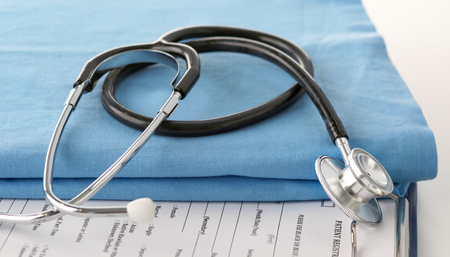 A stethoscope shaping a heart and a clipboard on a medical uniform, closeupの写真素材