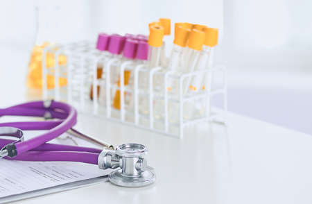 closeup of the desk of a doctors office with a stethoscope in the foreground and a bottle with pills in the backgroundの写真素材