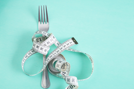 The fork is wrapped with a measuring tape on the table. Dietの写真素材