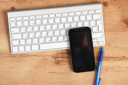 Modern aluminum keyboard on the wooden table in the officeの写真素材