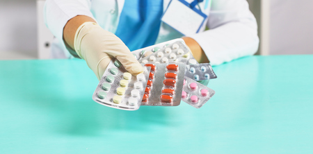 Female doctor hand hold pack of different tablet blisters at workplace. Panacea, life save service, prescribe medicament, legal drug store, disease healing, blood pressure concept. Letterbox viewの写真素材