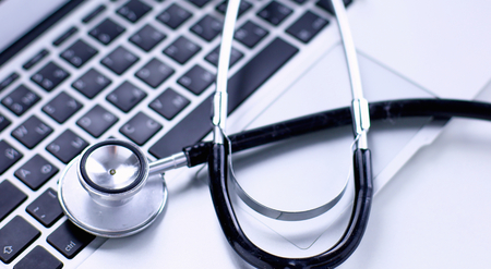 Stethoscope lying on a laptop keyboard in a concept of online mの写真素材