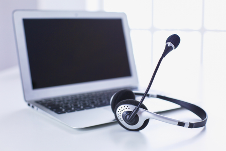Call center and customer service help desk. VOIP headset on laptop computer keyboardの写真素材