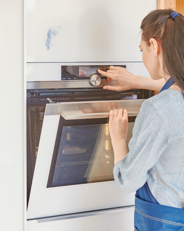 Beautiful woman in the kitchen, waiting with the front of the oven.の写真素材