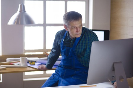 Engineer carpenter working on laptop and sketching projectの写真素材