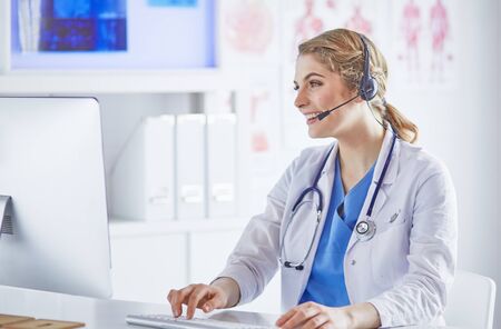 Portrait of a happy smiling young doctor in headset in officeの写真素材