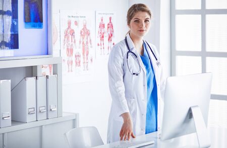Young woman doctor is standing with board with clipboard smilinの写真素材