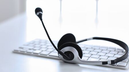 Communication support, call center and customer service help desk. VOIP headset on laptop computer keyboard.の写真素材