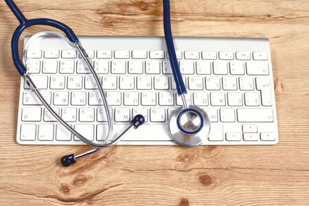 A medical stethoscope near a laptop on a wooden table, on whiteの写真素材