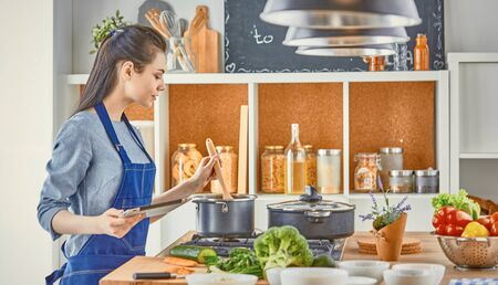 A young woman prepares food in the kitchen. Healthy food - vegeの写真素材