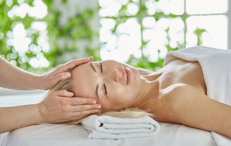 Beautiful woman with closed eyes getting a massage in the spa salonの写真素材