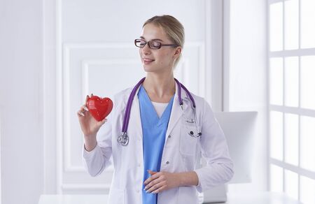 Doctor with stethoscope holding heart, isolated on white backgrの写真素材
