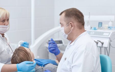 Doctor dentist treats teeth of a beautiful young girl patient. The girl on reception at the dentist. Doctor dentist treats tooth.の写真素材
